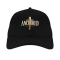 black Christian golf cap with gold cross and ANCHORED lettering, front view.