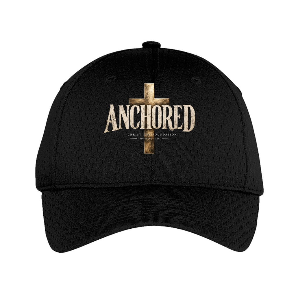 A black mesh baseball cap featuring a distressed gold cross and the word 'ANCHORED' on the front, with smaller text below reading 'CRAFTED BY ANCHOR 365'.