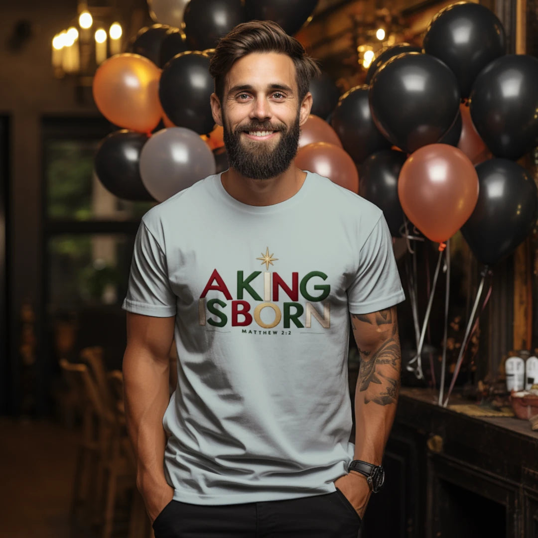 man wearing a light gray Christian Christmas T-shirt with 'A King Is Born' text, Bethlehem star, and Matthew 2:2.
